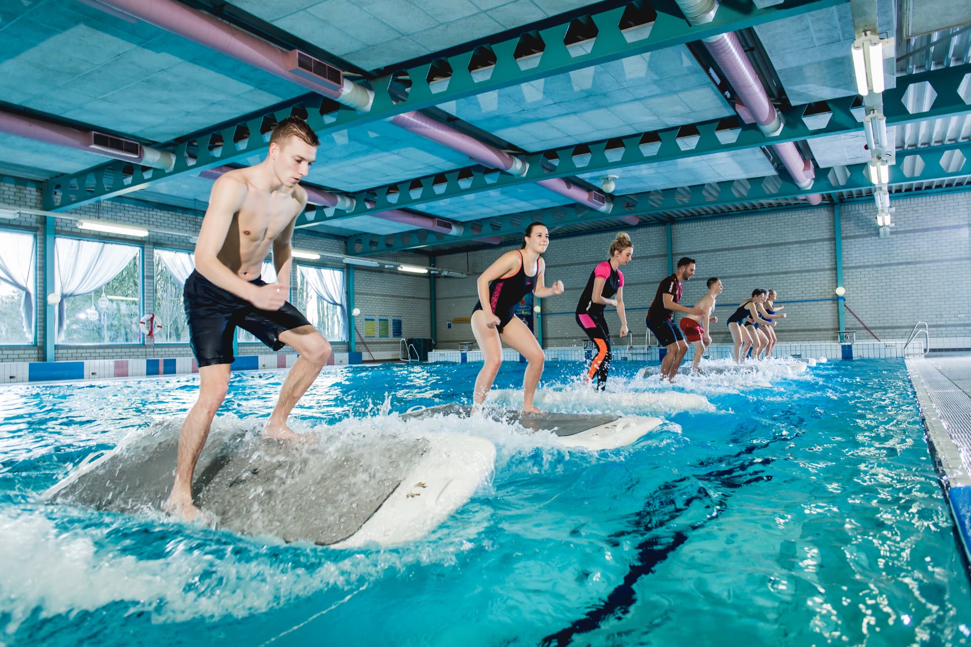 Groep sporters staat op FloatFit-boards in het zwembad van De Meerval