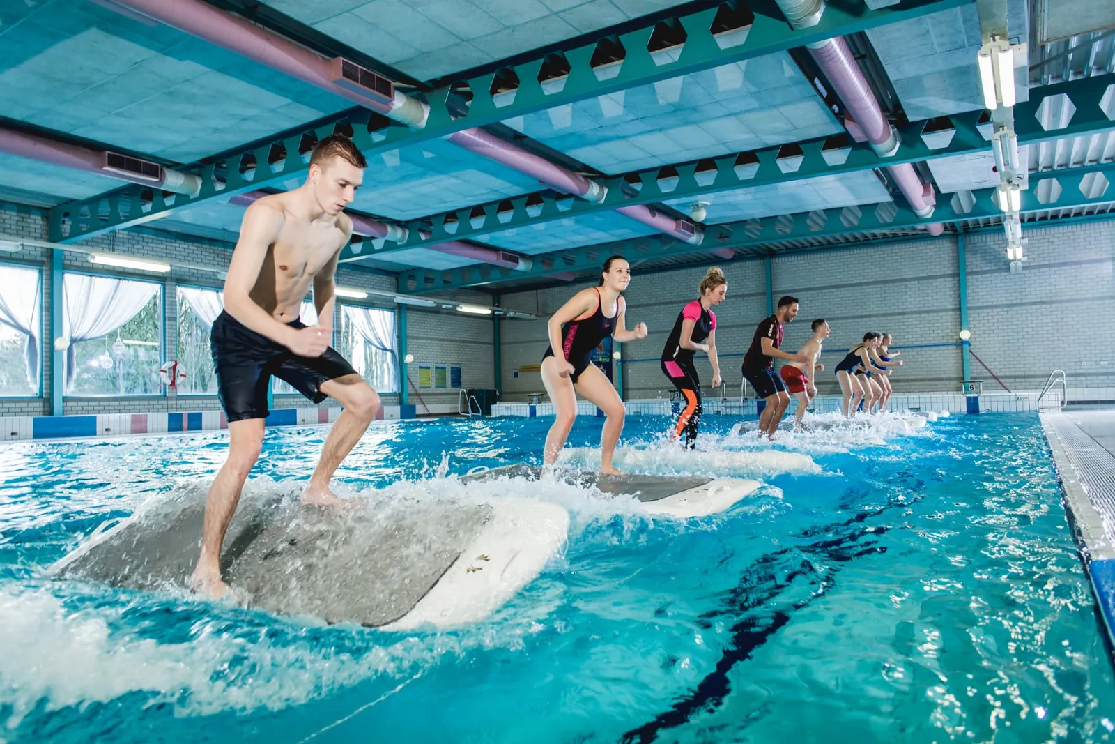 Groep sporters staat op FloatFit-boards in het zwembad van De Meerval