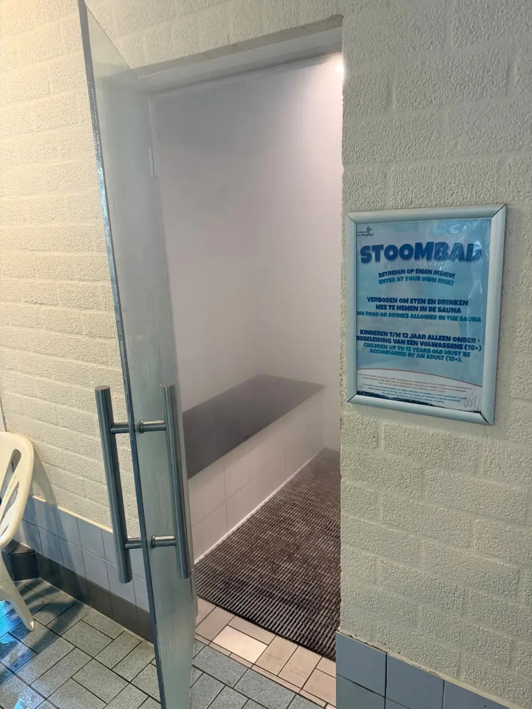 Ingang van het stoombad met glazen deur bij De Meerval