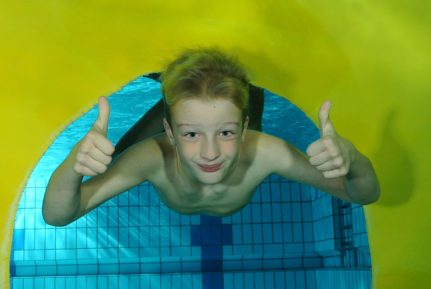 Kind steekt duimen op onder water