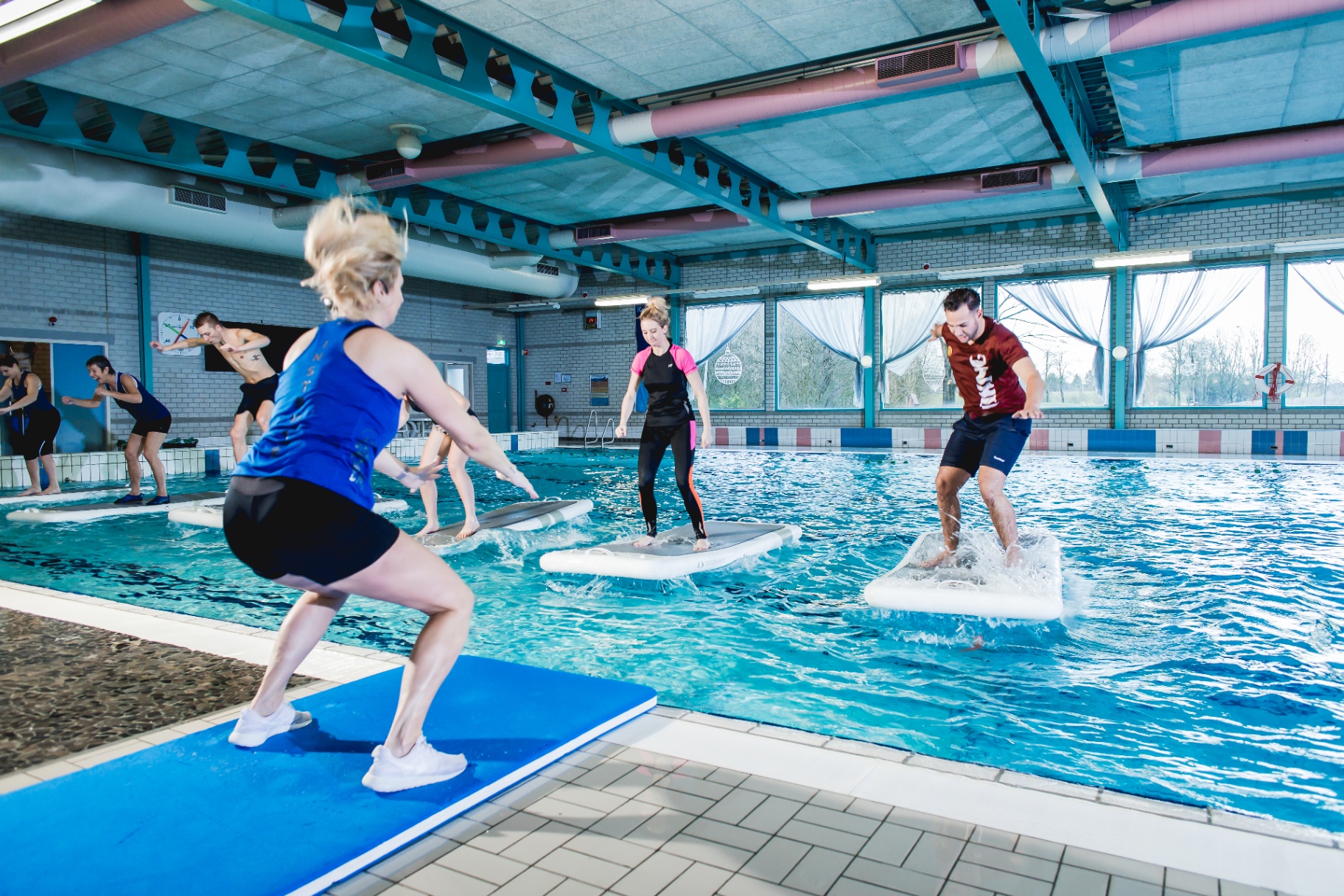 Groep deelnemers traint op FloatFit-mats in het wedstrijdbad van De Meerval